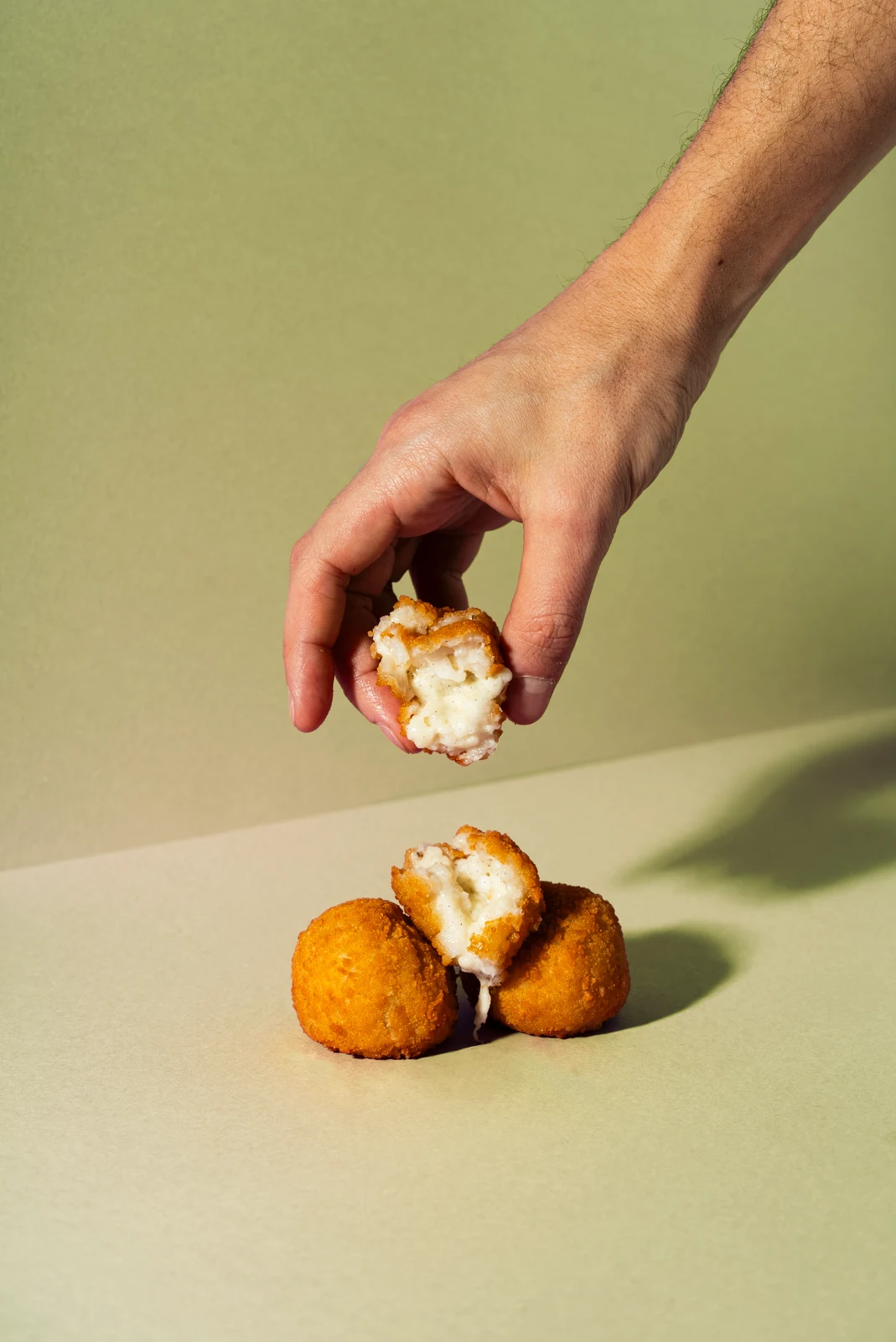 Three 50 g cacio e pepe mini supplì, one opened to show the pecorino cream